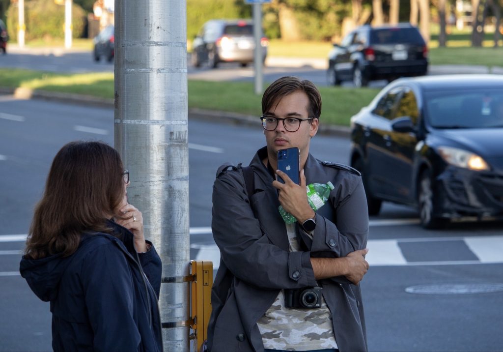 Charlie and Karen stand on a street corner and talk. 