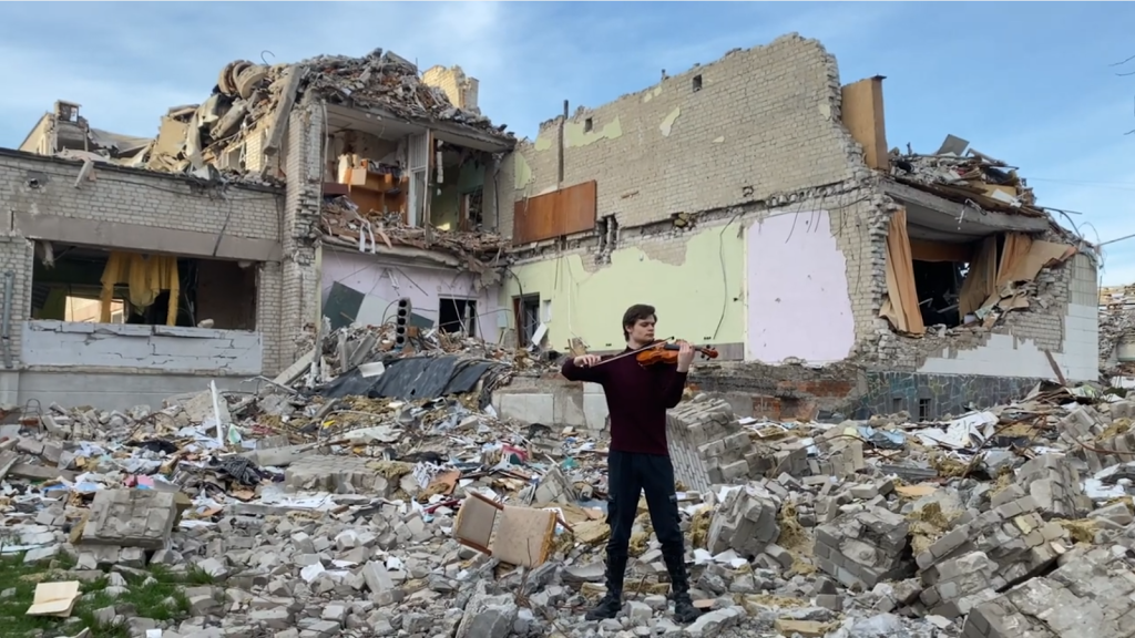 A man plays the violin in a Ukraine war zone. 