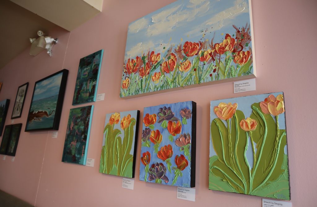 Paintings of tulips are on display on the cupcake stores walls