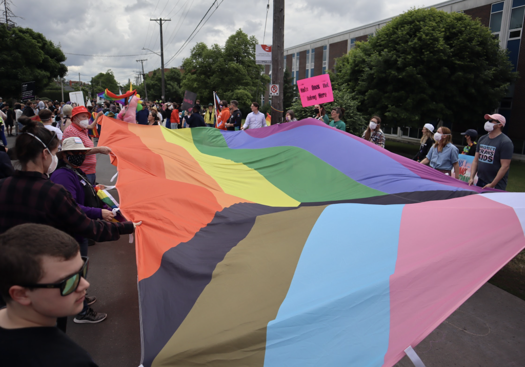 A large pride flag is carried down Broadview Avenue. 