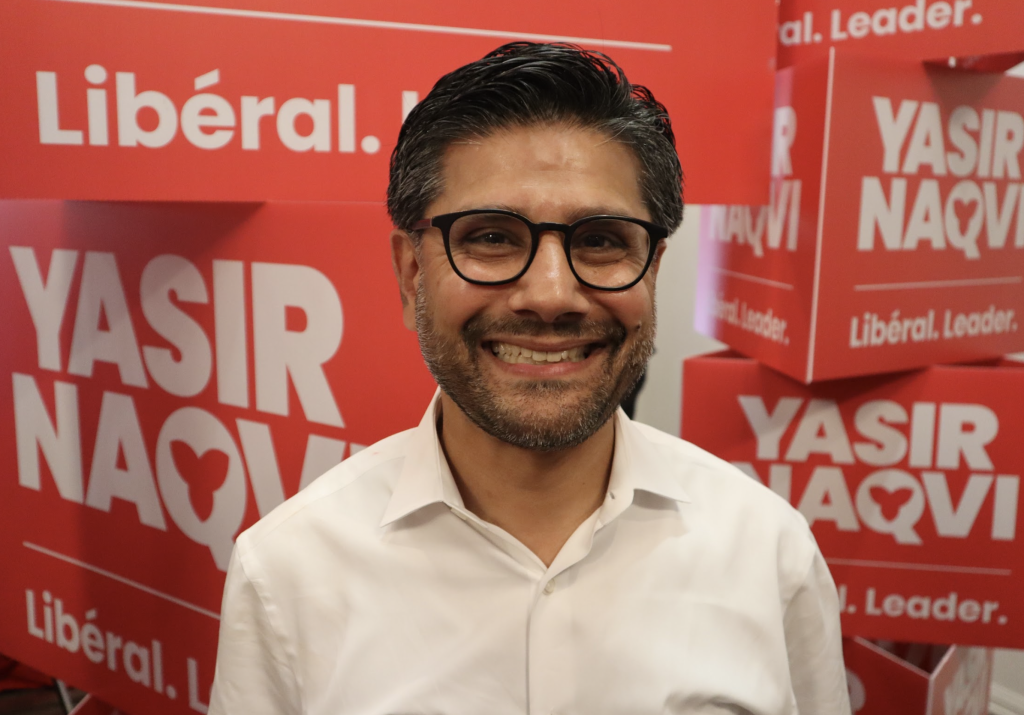 Yasir poses for a photograph next to his election signs.