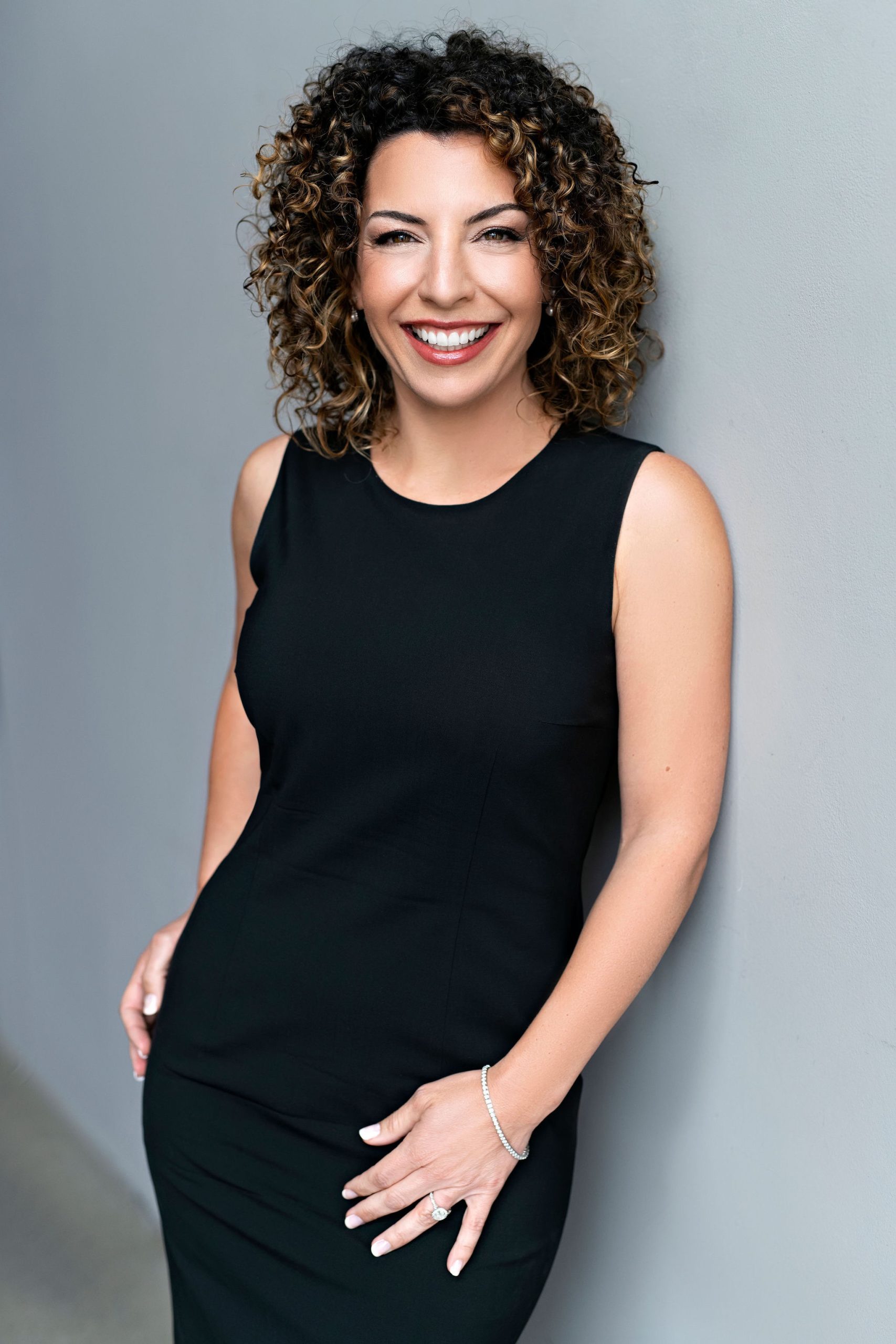 A photo of Kris Ouimet smiling next to a wall. 