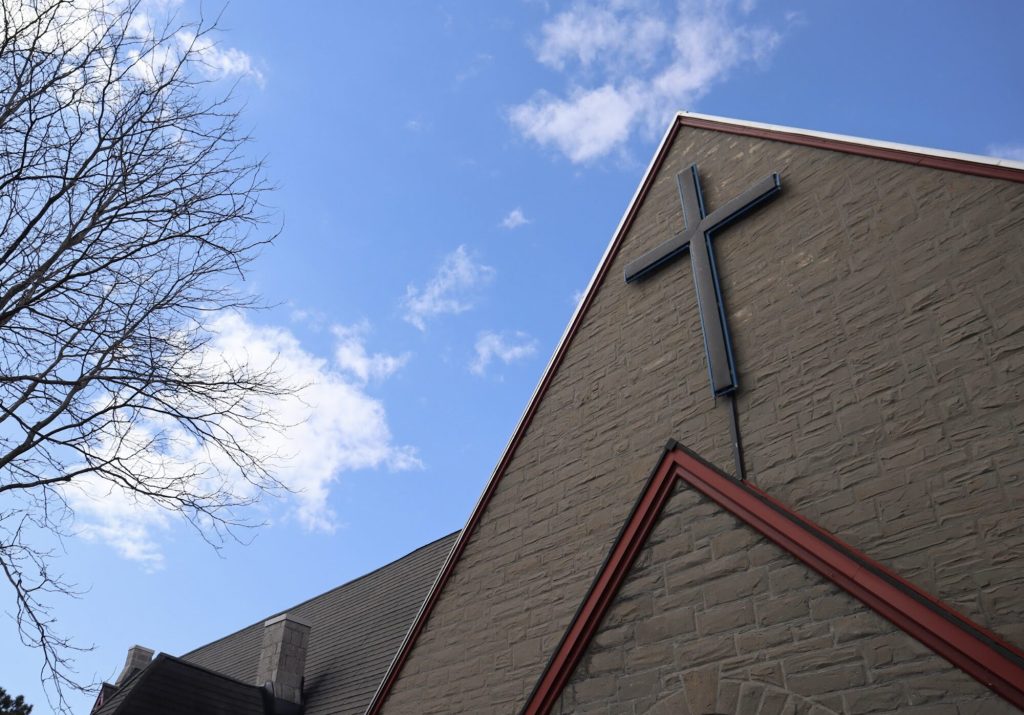 The cross on top of the church on a sunny day. 