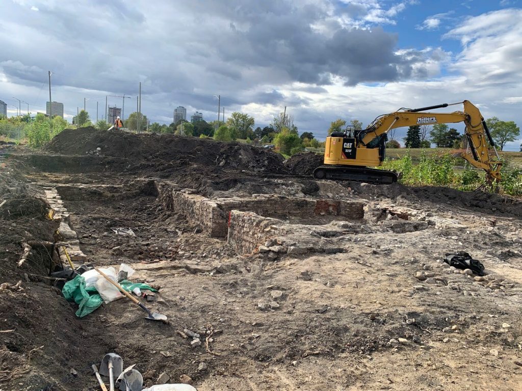 Construction machinery digs around an old foundation. 