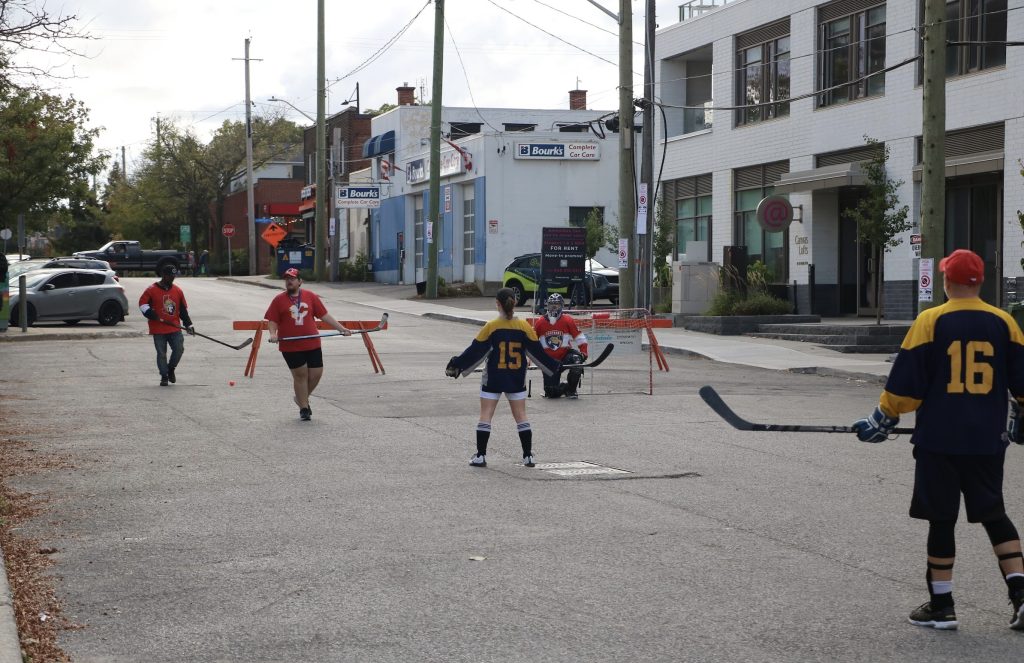 Five kids play ball hockey on the street near Parkdale park. 