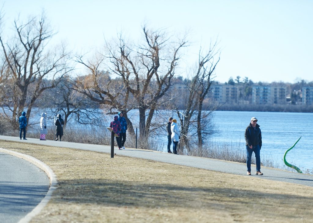 Runners and walkers on a trail. The Ottawa River is seen in the distance. 