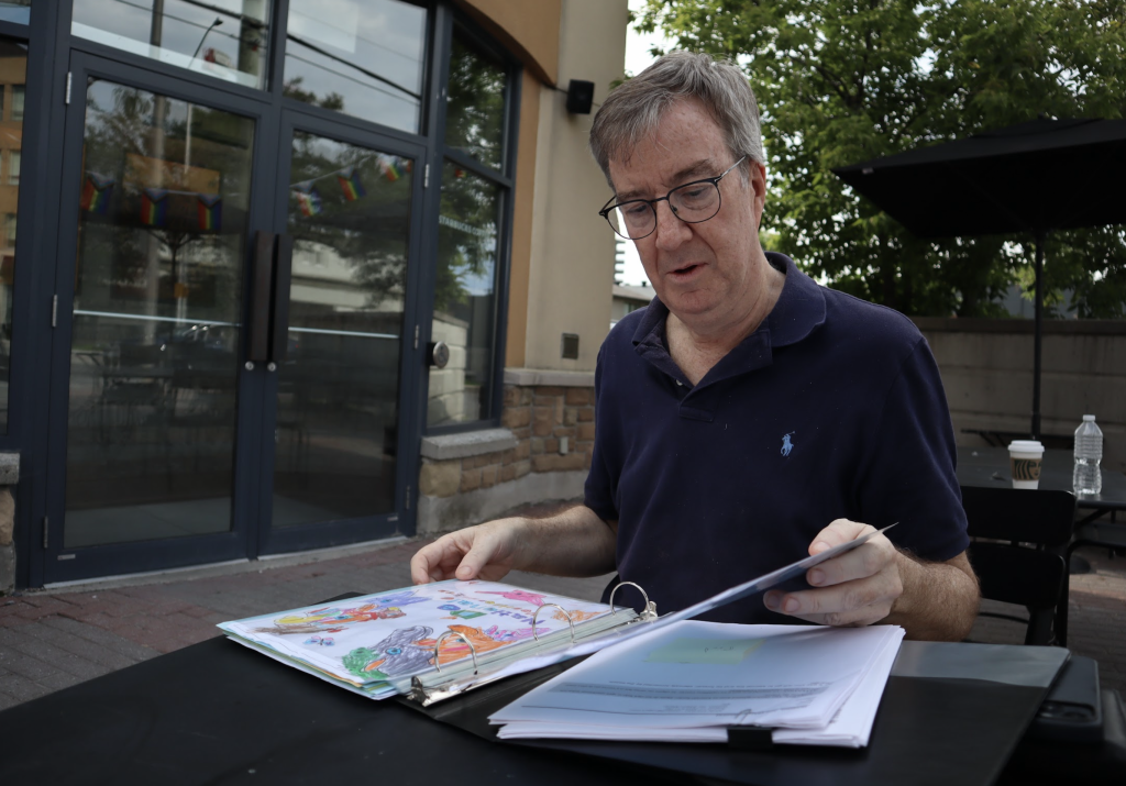 Jim Watson sits outside the Starbucks in Westboro and flips through a binder full or letters and drawings