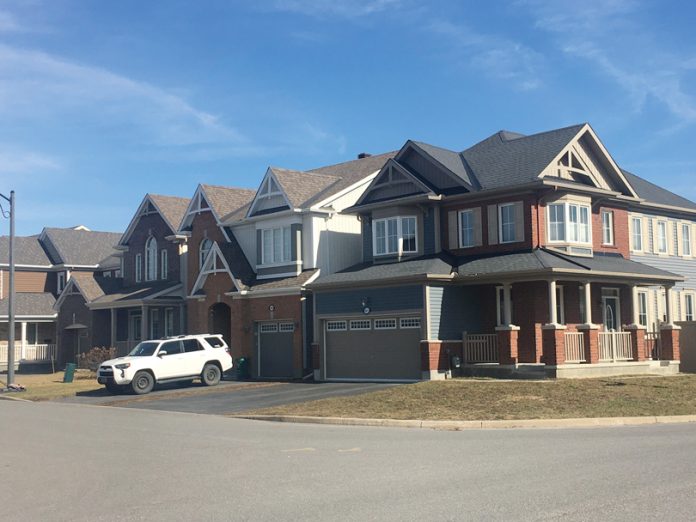 A row of townhouses is seen on a sunny day in Ottawa in a suburb|A professional headshot of Debra Wright against a white background