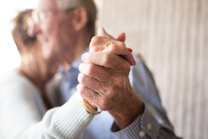 Portrait of senior couple embracing and dancing holding hands|