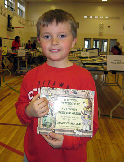 Liam Edwards, 7, of Westboro, picked up a book of nursery rhymes by Maurice Sendak. “I remember it from when I was a kid,” says mom and BookFest volunteer Kim Edwards.