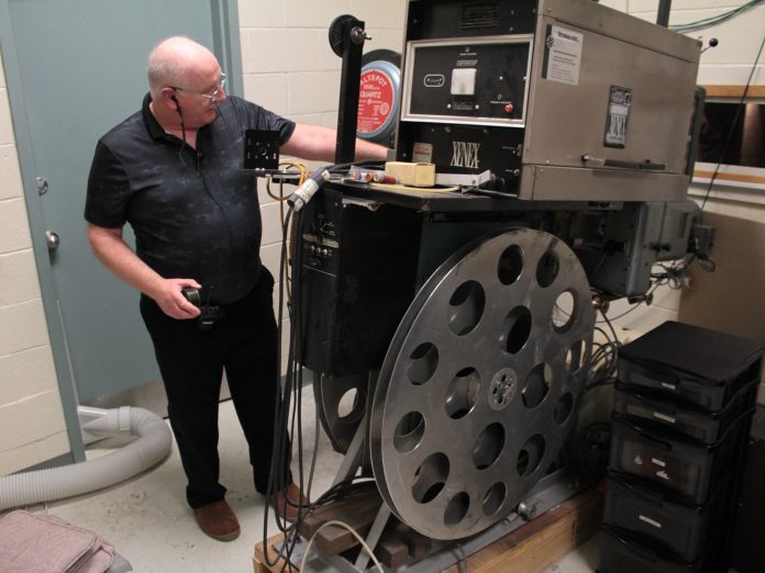 Projection operator Julian Gumley demonstrates how to work the 35mm projector that the OFC used in its earliest days.|OFC co-founder Jim McNeill with grandkids Zoe