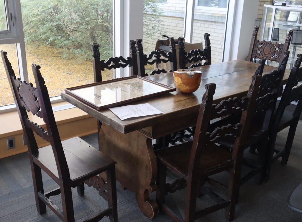 An old wooden table with eight chairs. 