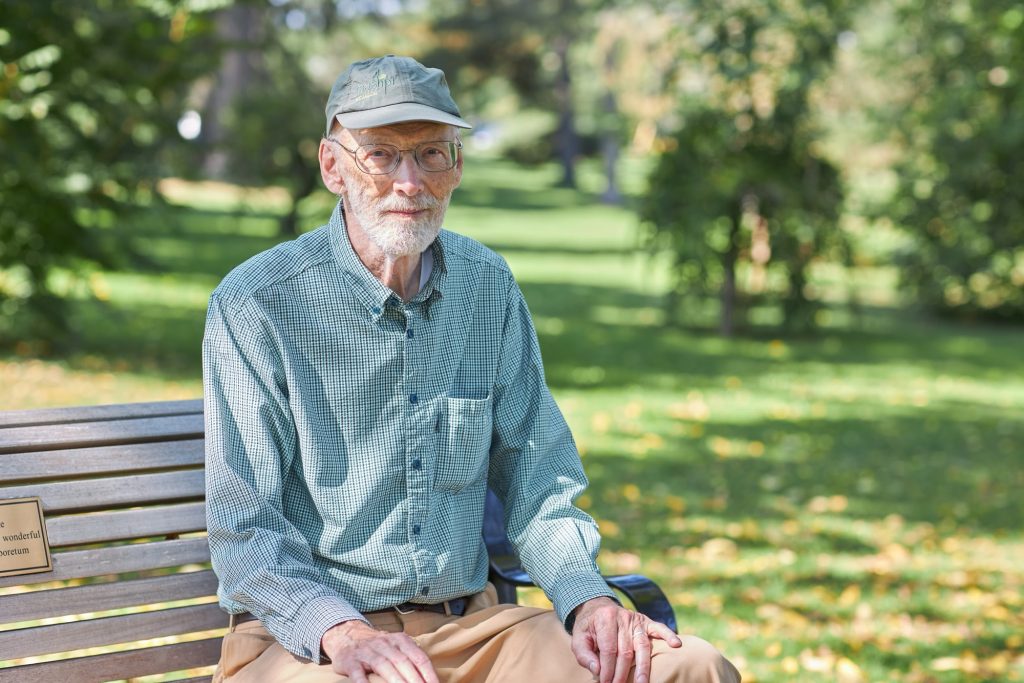 Eric sits on a bench in a park.