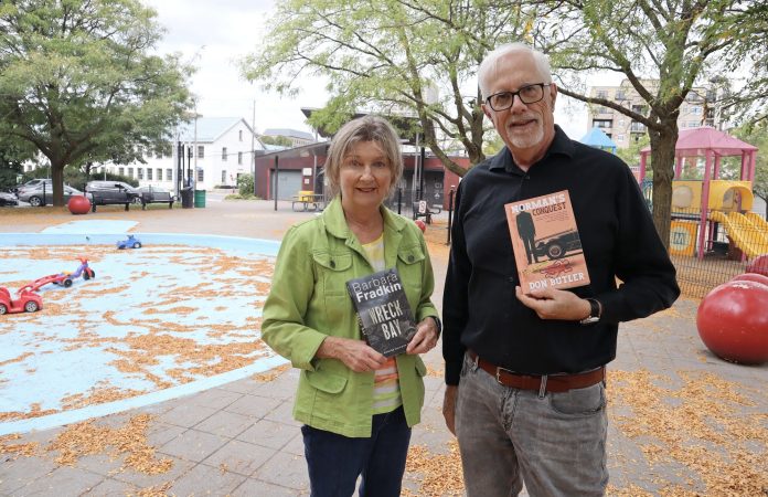 Barbara and Don hold up copies of their books in Parkdale Park.