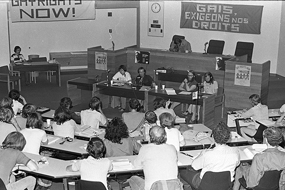 A black and white photo of peoooe sitting in a lecture hall.