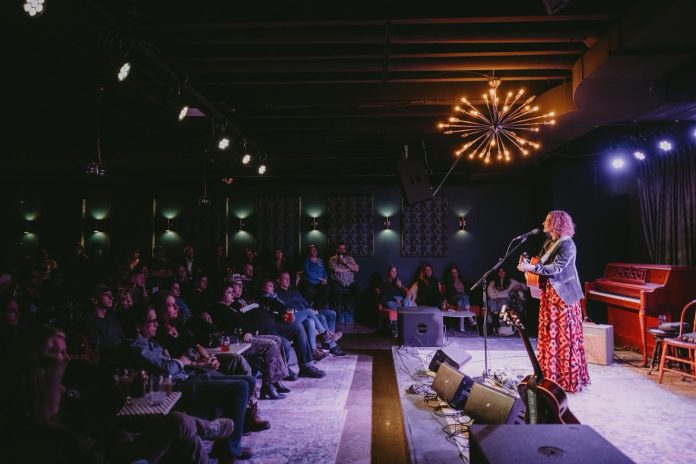 A woman performs on a stage as onlookers watch.