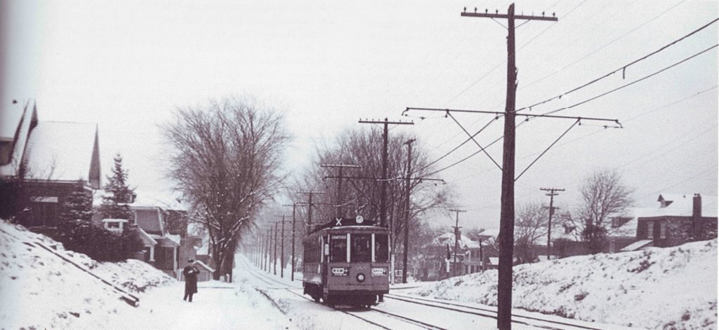 A streetcar passes through a residential neighborhood on a winters day.