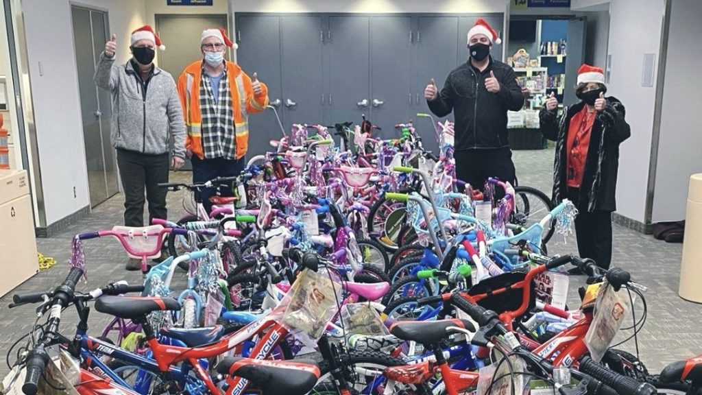 Four people stand with a large collection of donated bikes.